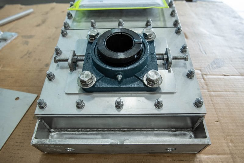 Machined and welded stainless assembly with mounted bearing housing and precision bolt pattern.